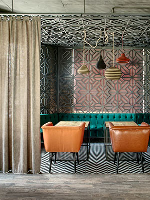 57741343 - wonderful interior in a loft style in a mexican restaurant. there is a zone decorated with metal lattices and curtains. in the zone there are green sofas, brown chairs, wooden tables and multi-colored lamps over them. on the floor there is a gray parquet,